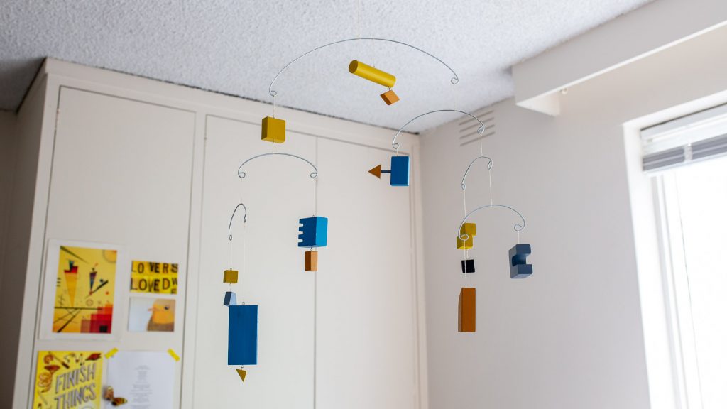A kinetic hanging mobile made of coloured wooden blocks.